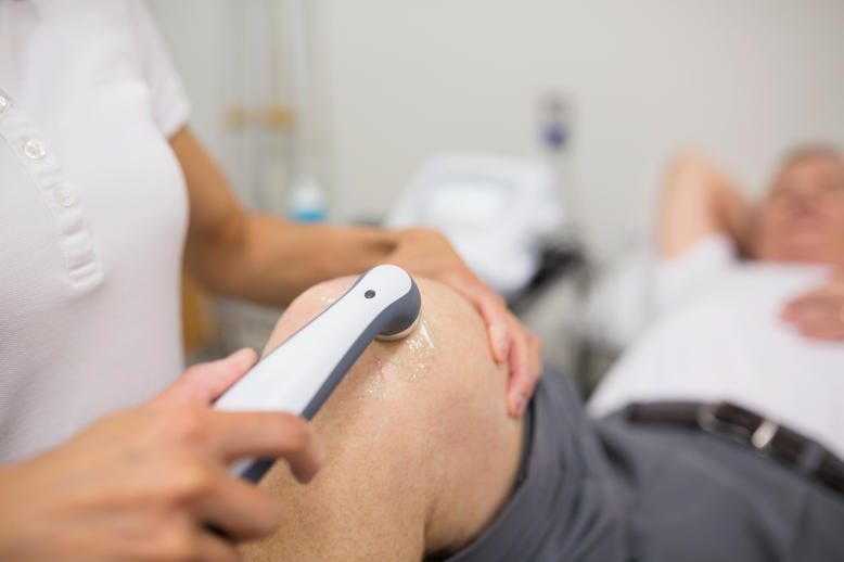 Physical therapist using ultrasound on patient's knee